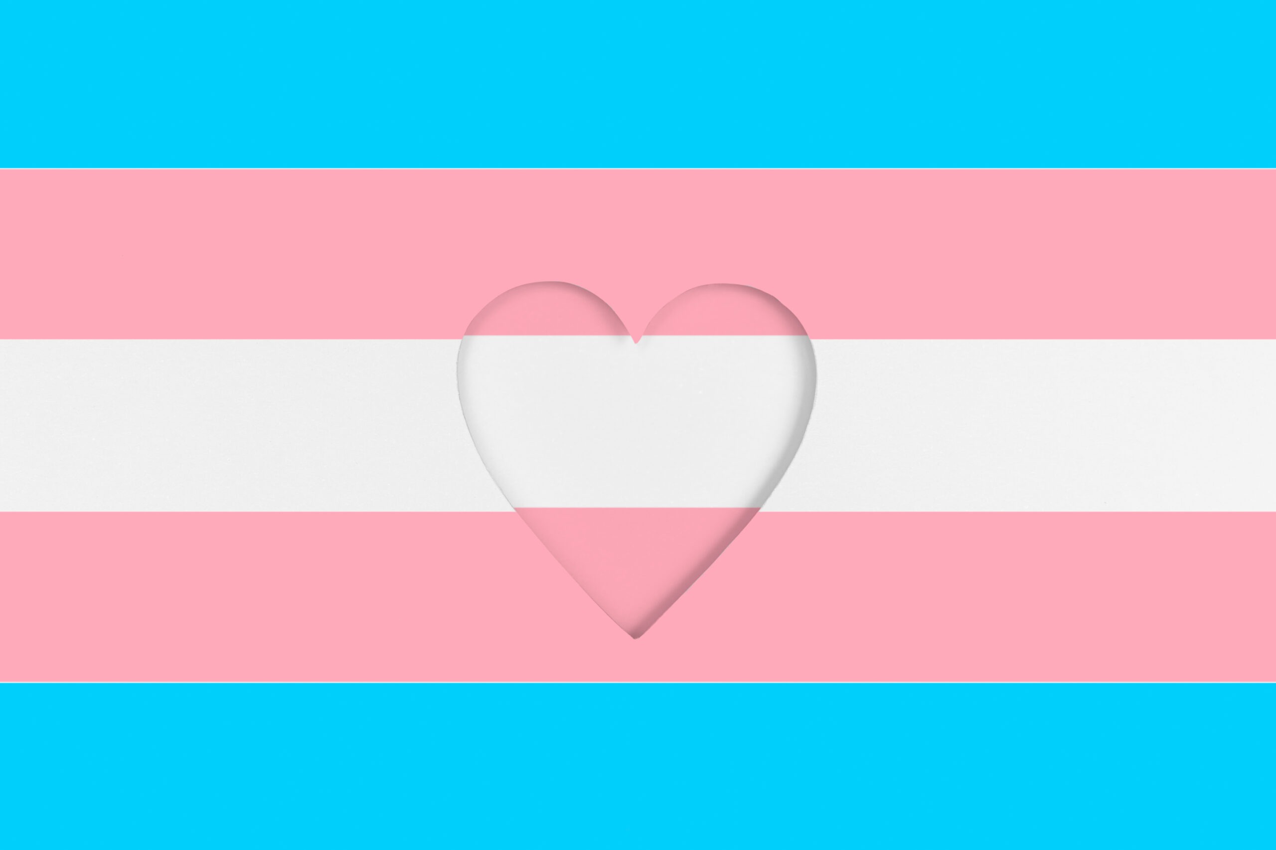 Transgender flag background. Printed cardboard with die-cut heart shape. Top view image of a trans pride flag with a heart on it